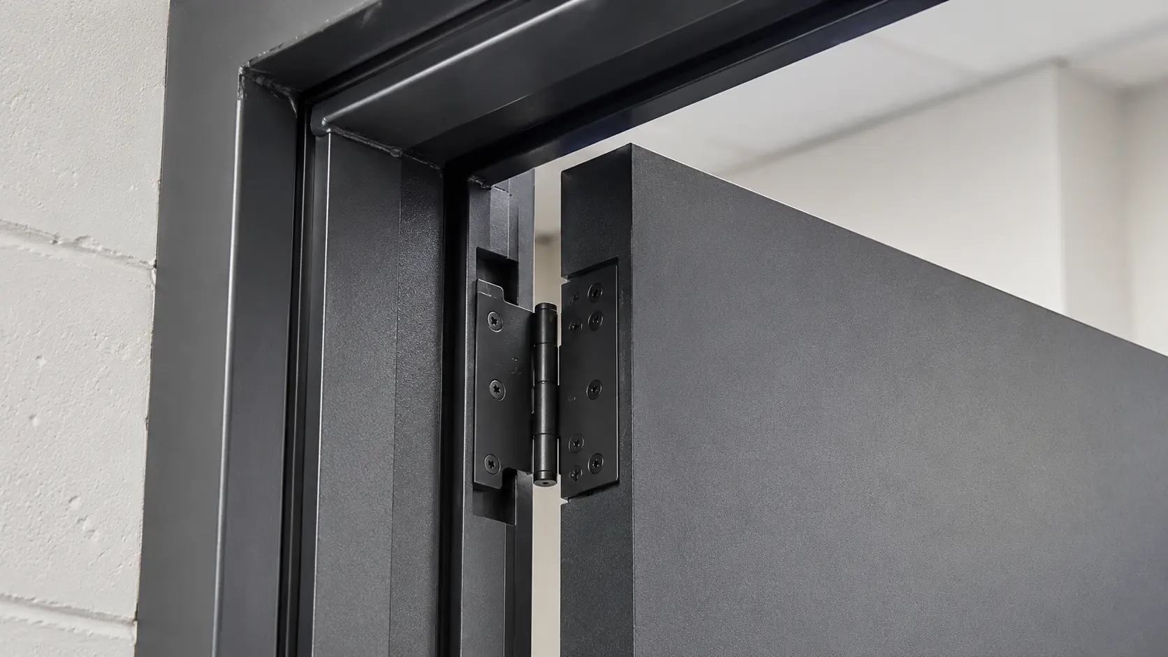 Close-up photograph of a metal door frame jamb showing hinge and strike preparation